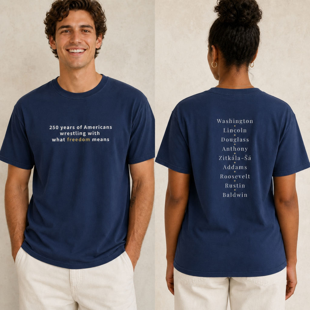 A navy blue graphic t-shirt shown on two models, front and back. The front features white text reading '250 years of Americans wrestling with what freedom means'.
